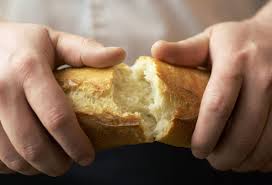 Dłonie przełamujące chleb.