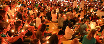 Młodzież w półmroku siedzi po turecku z płonącymi świeczkami na spotkaniu modlitewnym w ducchu Taizé.