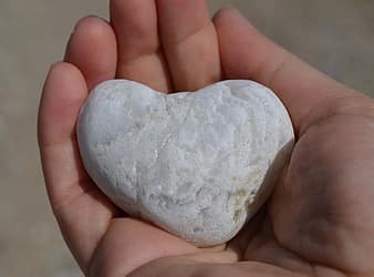 Na wyciągniętej dłoni biały kamień w kształcie serca