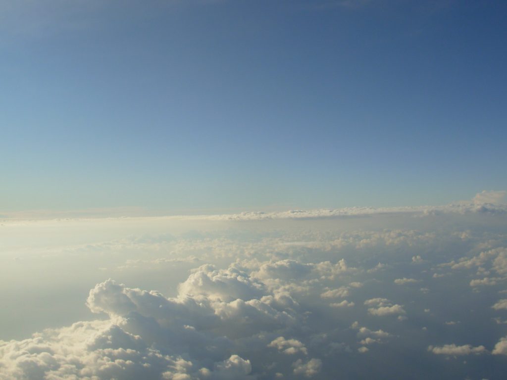 zdjęcie z lotu samolotem, ponad białymi chmurami rozświetlone błękitne niebo