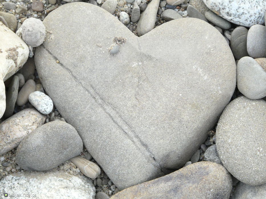 wśród szarych drobnych kamieni, większy kamień w kształcie serca