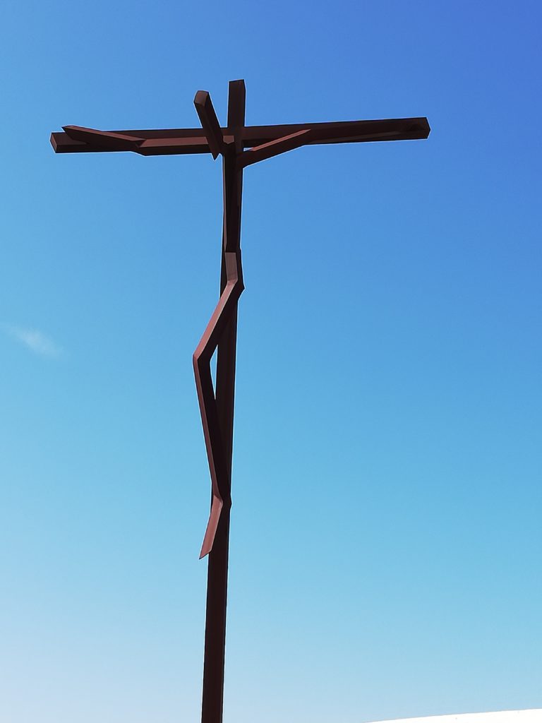 na niebieskim niebie, brązowy krzyż z Chrystusem Ukrzyżowanym - sztuka współczesna 