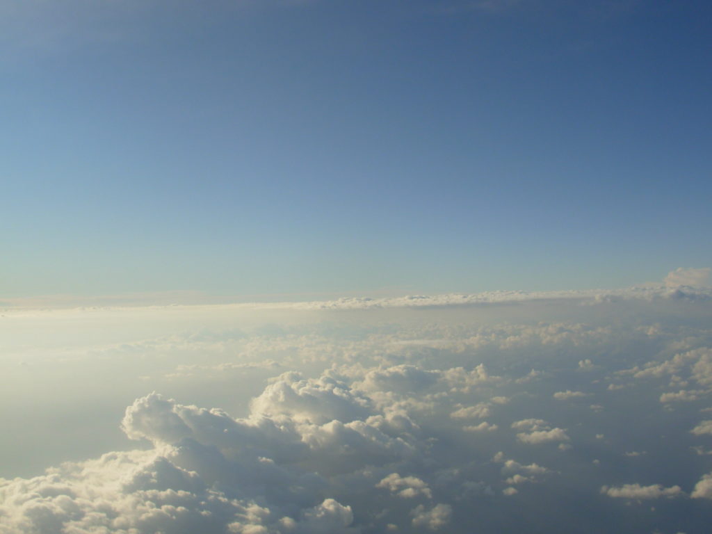 białe chmury nad nimi lazurowe niebo, zdjęcie z okna samolotu 